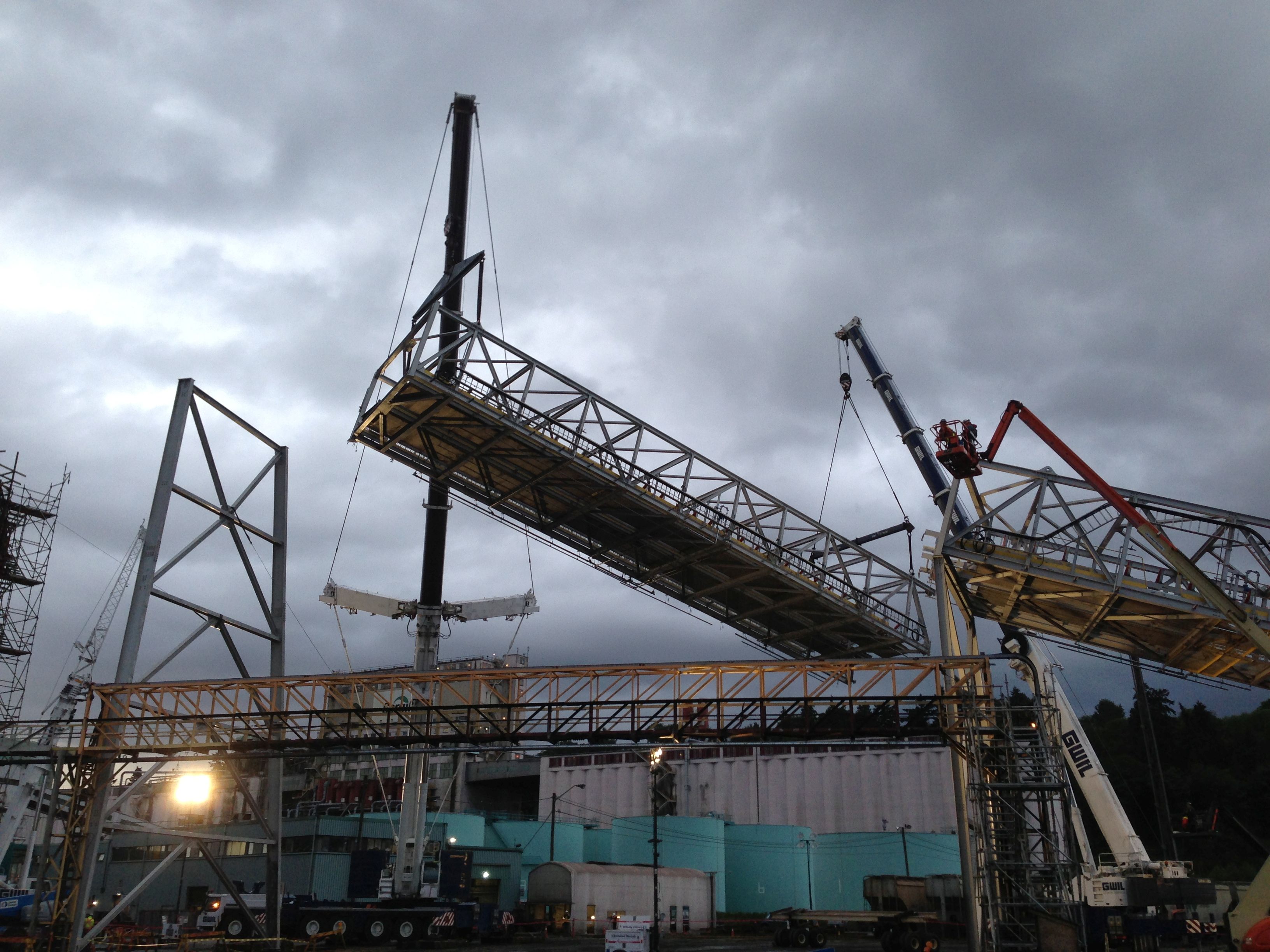 Large structural steel module being lifted by cranes during construction