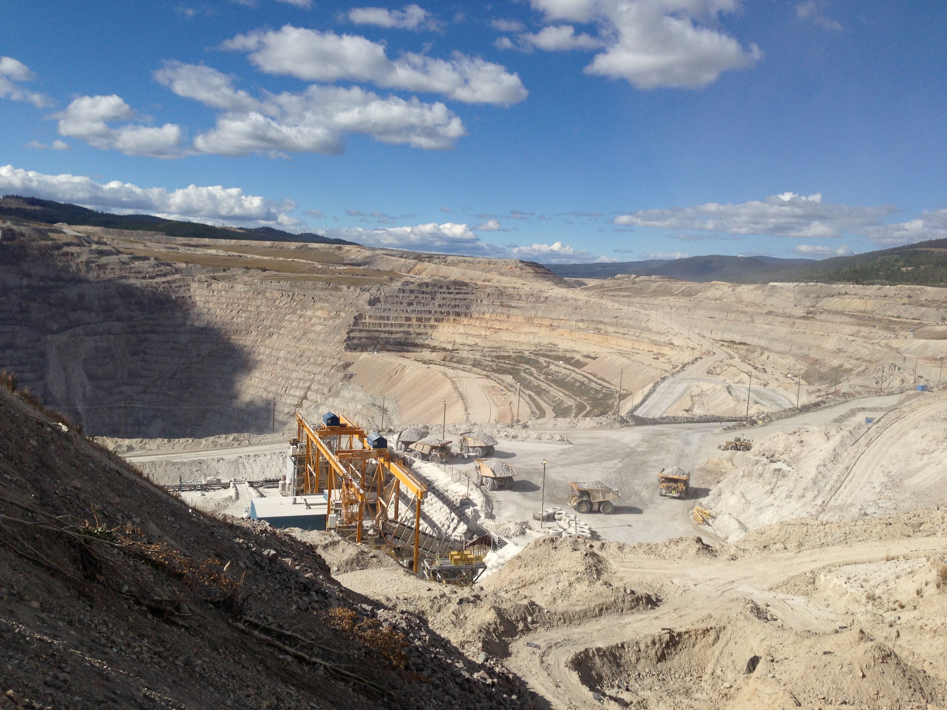 Open pit mine with conveyor system and haul trucks